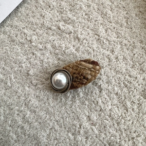 Detailed macro view of tweed fabric hairpin with vintage pearl button on soft fleece