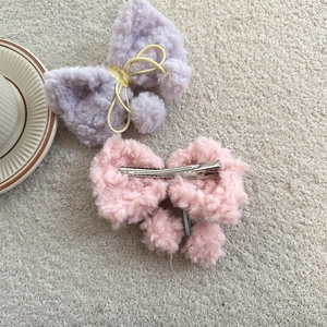 Dettaglio di fermagli per capelli in lana di agnello con fiocchi di peluche viola e rosa