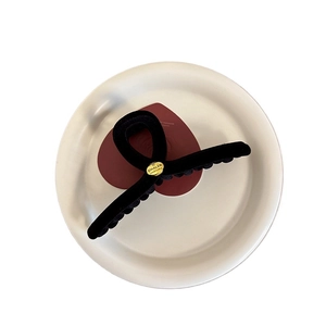 Classic black velvet hair claw clip with a gold logo tag displayed on a red heart card