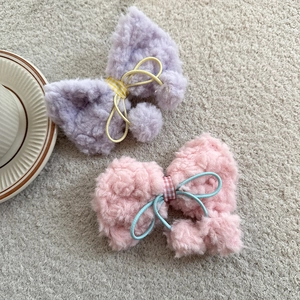 Dettaglio ravvicinato di elastici per capelli con fiocchi in lana di agnello viola e rosa
