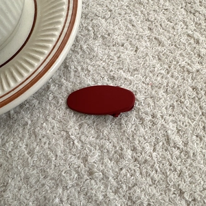Elegant deep red matte oval hair clip placed on a white faux fur textured background