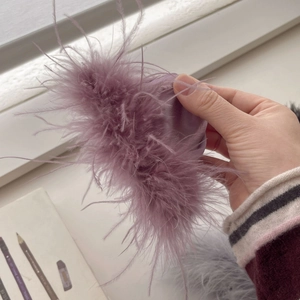 Elegant purple feather hair claw clip with satin base shown in a hand-held display