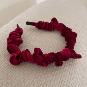 Detail of burgundy velvet scrunchie headband showing the rich pleated fabric texture