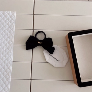Elegant black velvet bow hair tie with gold metal ring on a white minimalist background