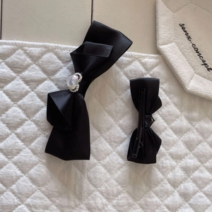 Détail de barrettes nœuds en satin noir avec perle cœur et pince crocodile en métal