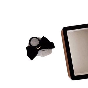 Elegant black velvet bow hair scrunchie with a gold button on a white display card