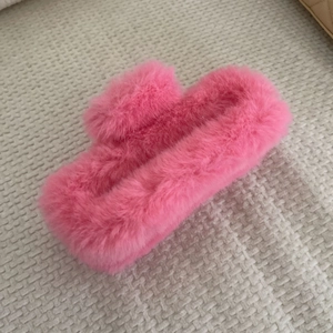 Détail de la texture douce en fausse fourrure rose sur une grande pince à cheveux