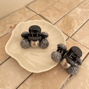 Dettaglio di due piccole mollette per capelli con cristalli grigi e perle dorate