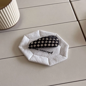 Detail view of woven checkerboard hair clip in black and silver on a white fabric pad