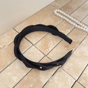 Elegant black satin pleated headband with pearl accents on a neutral textured surface
