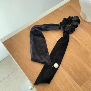 Elegant black velvet scrunchie with long ribbons and large pearl charms on a wooden table
