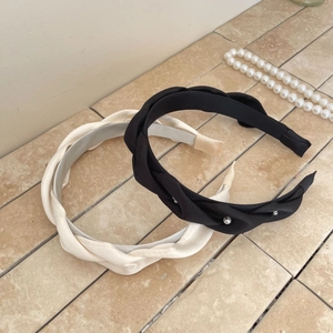 Detail of twisted fabric headbands in black with pearls and soft cream on stone tile