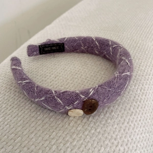 Detailed macro view of purple knit headband texture with vintage buttons and handmade label