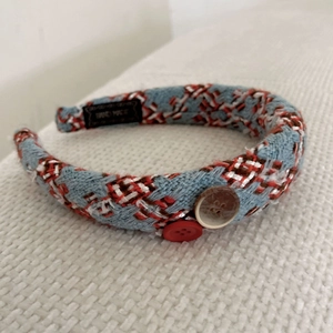Close-up of a thick knitted headband with brown and red buttons and a handmade label