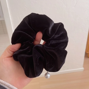 Close-up of black velvet scrunchie with elegant pearl charm and silver ring