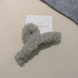 Detailansicht der weichen grauen Plüschtextur einer flauschigen Haarklammer für Damen