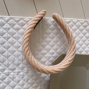 Serre-tête large en tricot beige avec motif à chevrons pour femme sur fond chaleureux