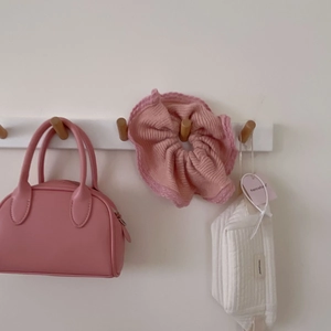 Pink mink fur scrunchie and quilted cosmetic bag set shown hanging on wooden hooks