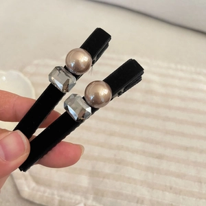 French velvet hair clips with pearls and rhinestones shown in hand on beige background