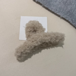 Nahaufnahme der beigen Plüsch-Haarklammer mit Kreuz-Design für herbstliche Frisuren
