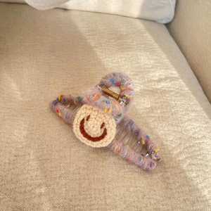 Plush purple yarn hair claw clip with a cute crochet smiley face for autumn and winter