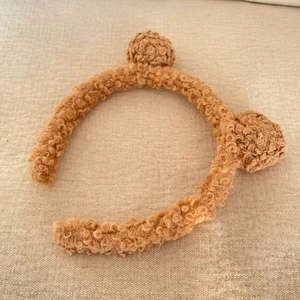 Close-up of warm brown teddy fleece headband with cute fuzzy bear ears for skincare