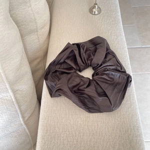 Chocolate brown oversized scrunchie with textured matte fabric on a soft beige background