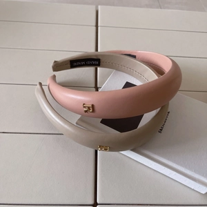 Detail showing the fine leather texture and golden metal R-logo on the padded headband