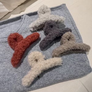 Nahaufnahme von fünf Plüsch-Haarklammern in Herbstfarben auf weichem Strickhintergrund