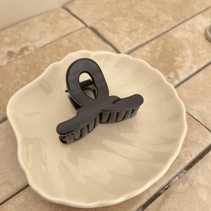 Pince à cheveux noire brillante dans un plateau décoratif en coquille sur carrelage