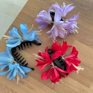 Lot de pinces à cheveux banane à fleurs bleu, violet et rouge sur fond de bois rustique