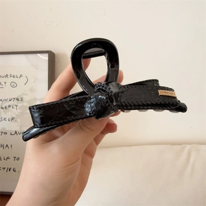 Elegante pinza per capelli con fiocco in pelle nera e targhetta in metallo dorato