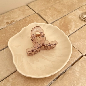 Pince à cheveux rose translucide minimaliste dans un plat décoratif blanc élégant