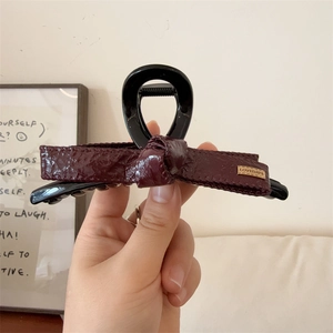 Elegante pinza per capelli con fiocco in ecopelle bordeaux e nero e dettaglio dorato