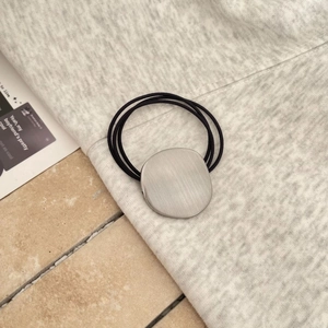Detail of three-strand elastic hair tie featuring a matte brushed metal oval ornament