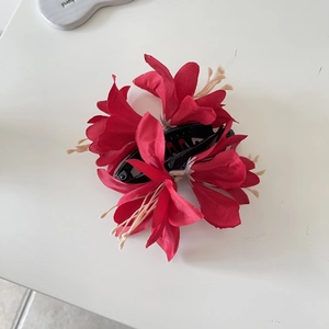 Vue détaillée de dessus d'une pince à cheveux fleur rouge avec des étamines crème