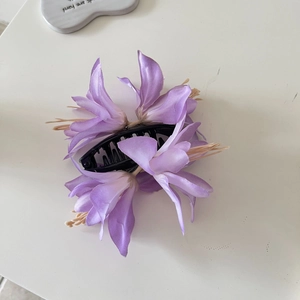 Vue détaillée de fleurs de lys en tissu violet clair sur une pince à cheveux noire