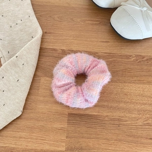 Detail of soft mohair texture scrunchie in pink gradient on a natural wood background