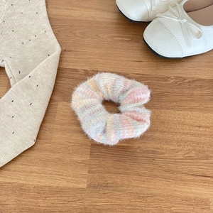 Macro detail of a soft mohair scrunchie with pastel gradient colors on wood floor