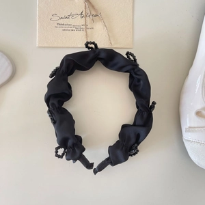 Detail of black pleated satin headband with sparkling crystal beads and subtle luster