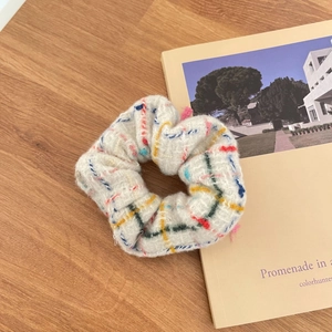 Detailed texture of a beige plaid scrunchie made of premium knitted fabric on wooden table