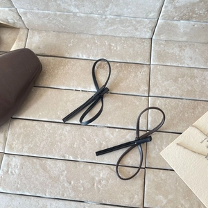 Minimalist black and brown leather bow duckbill hair clips for women on a stone surface