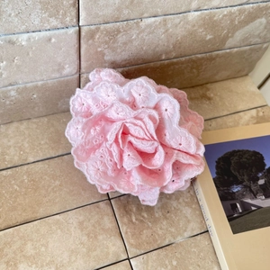 Elegant pink lace flower hair clip accessory styled on a book for a chic look