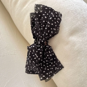 Detailed view of layered black polka dot chiffon bow clip with high-quality fabric texture