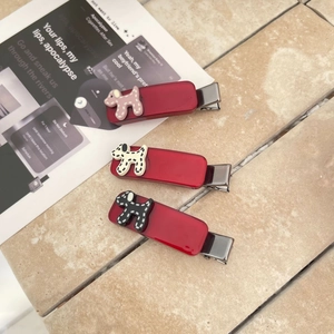 Dettaglio di tre fermagli per capelli in resina rossa con simpatici cagnolini