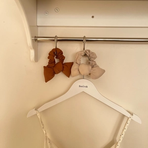 Vue détaillée de chouchous à nœuds en coton caramel et beige sur un cintre