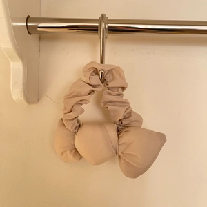 Vue détaillée d'un chouchou à nœud en coton beige avec une texture plissée douce