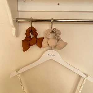 Lot de deux chouchous nœuds en coton marron et beige suspendus sur un portant en métal