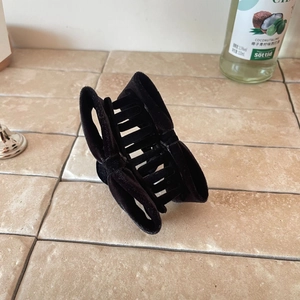 Elegant black velvet bow hair claw clip for women on a textured stone surface