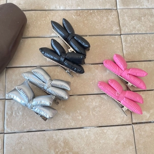 Détail de pinces à cheveux nœuds rembourrés en noir, argent et rose avec clip métallique robuste